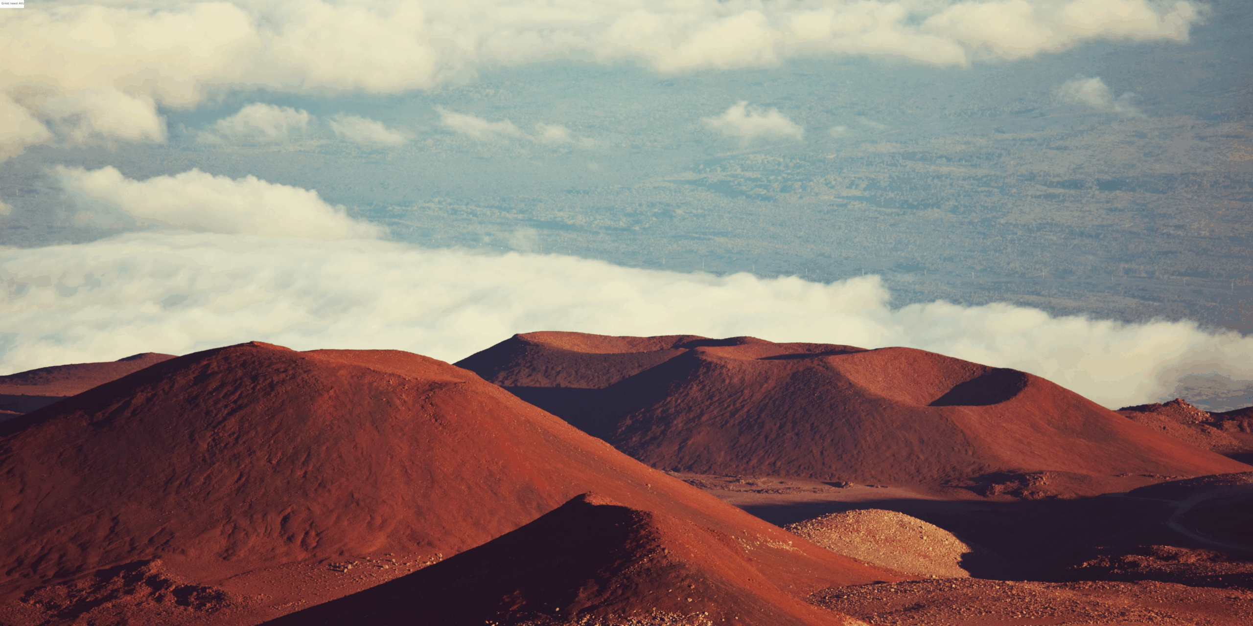 Mauna Kea on Hawaii Island - a scenic shot from above the red dirt colored mountains with the clouds in the distant background